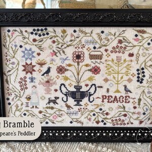 May include: Framed cross-stitch sampler with a black ornate frame. The sampler features a floral and bird design with the word "PEACE" stitched in the center. The text "Spring Bramble by Shakespeare's Peddler" is in the lower left corner.