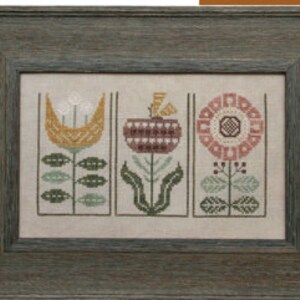 May include: Framed cross-stitch artwork featuring three stylized floral designs in muted tones. The flowers are set against a neutral background within rectangular frames. The frame is a weathered, muted teal color, adding a rustic touch to the piece.