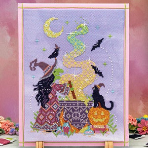 May include: A cross-stitch pattern featuring a witch stirring a cauldron with a black cat and a jack-o'-lantern. The background is a purple sky with stars and a crescent moon.