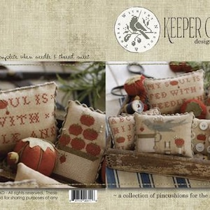 May include: A collection of 10 small, handmade pincushions in a wooden box. The pincushions are made of fabric and feature various designs, including a bird, a key, and the phrase "My soul is fed with needle and thread".