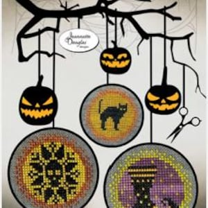 May include: A cross stitch pattern chart titled Halloween Dots 4-5-6 by Jeannette Douglas Designs. The image features black silhouettes of jack-o'-lanterns and three circular stitched designs including a black cat, a skull, and a witch's boot.