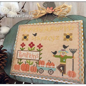 May include: Cross-stitch embroidery design featuring a scarecrow with a rake, pumpkins, and the text "Every Wish Filled This Thanksgiving".
