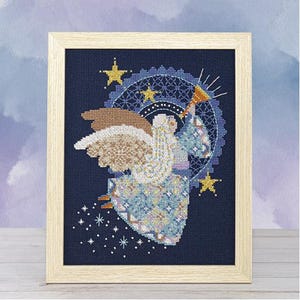 May include: Cross-stitch artwork of an angel in a wooden frame. The angel is depicted with detailed wings, a flowing gown, and a halo, set against a dark blue background with stars and a decorative circular pattern. The artwork is framed in a light-colored wooden frame.