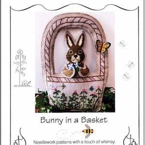 May include: A cross-stitch pattern featuring a brown bunny holding a flower, sitting in a basket with a butterfly and bees. The pattern is titled "Bunny in a Basket" and is from "The Needle's Notion" needlework patterns.
