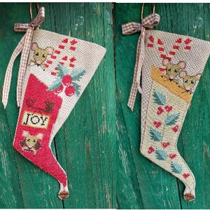 May include: Four handmade Christmas stockings with a mouse theme. Each stocking features a different design with red, green, and white colors. The stockings are decorated with candy canes, holly, and bells.