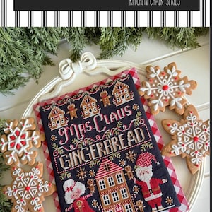 May include: A cross-stitch design featuring "Mrs. Claus Gingerbread" with a navy background, gingerbread house and Santa Claus illustrations. The design is surrounded by snowflake-shaped gingerbread cookies. The text "Stitching with the Housewives" is at the top.