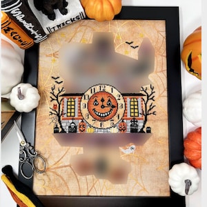 May include: A framed cross-stitch design featuring a spooky clock face with a grinning pumpkin. The clock is surrounded by a cobweb design and other Halloween imagery, including a house, pumpkins, and bats.