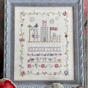 May include: Cross-stitch embroidery framed in a gray wood frame. The design features a red, white, and blue American flag, a bird, and the text "Oh Sweet Land of Liberty".
