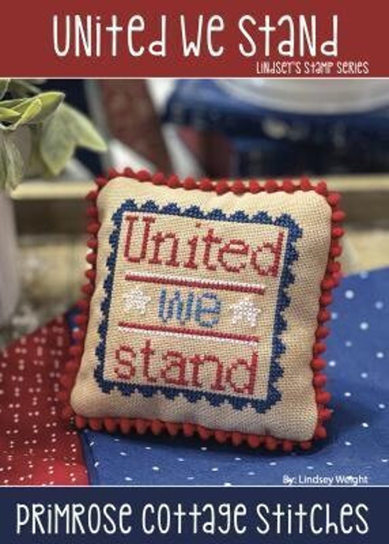 May include: A cross-stitch pillow with a red, white, and blue design that says "United we stand". The pillow is surrounded by red, white, and blue fabric.