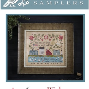May include: A framed cross-stitch sampler with a patriotic theme. The sampler features a red, white, and blue color scheme and includes the text "This land we love so vast and free" and "God Bless the USA".
