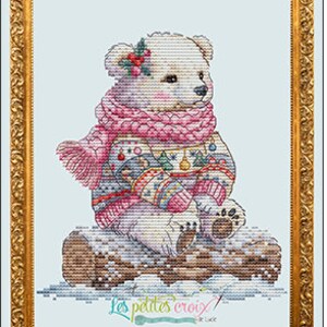 May include: A white polar bear wearing a pink scarf and a colorful sweater with a Christmas tree design sits on a log in the snow. The image is framed in gold and has the text "Les Petites Croix" at the bottom.