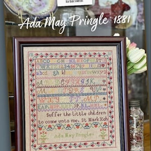 May include: A framed cross-stitch sampler with a cream background and colorful embroidery. The sampler features the alphabet, numbers, and the quote "Suffer the little children to come unto me. St Mark Xch". The sampler is signed "Ada May Pringle 1881".