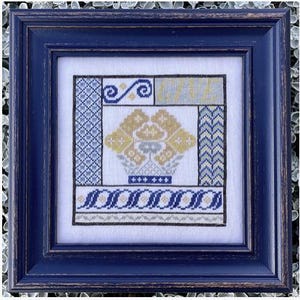 May include: A framed cross-stitch embroidery with a blue and yellow floral design. The embroidery is framed in a dark blue frame.