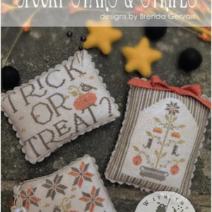 May include: Three rectangular fabric pin cushions with cross-stitch embroidery. One reads TRICK OR TREAT? with a pumpkin. Another features a potted plant with candy corn. The third has a pumpkin and star pattern. Includes a round logo tag.