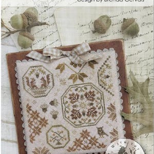 May include: A cross-stitch sampler titled "Quaker Snippets No. 1" by Brenda Gervais. The design features geometric patterns, leaves, and acorns in shades of brown and green. A small round emblem with a bird is also included.