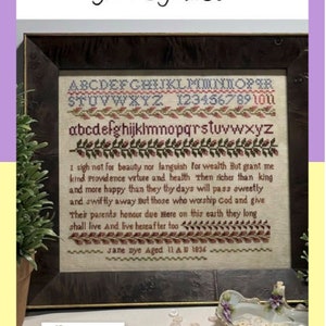 May include: A framed cross-stitch sampler with the text "Jane Dye Aged 11 A 1836" and a poem about virtue and health. The sampler is surrounded by a wooden frame and is displayed on a table with a small dish of buttons.