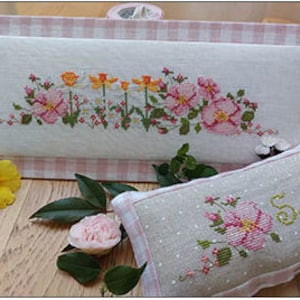 May include: Two embroidered pieces with a spring theme. A rectangular piece with a floral border of pink and yellow flowers and a small pillow with a single pink flower and the word "Spring" in cursive.