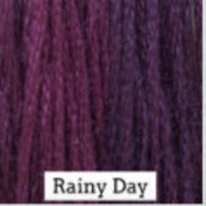 May include: A skein of purple and pink yarn with a gradient color effect. The yarn is labeled "Rainy Day".