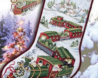 May include: A Christmas stocking with a Santa Train design. The stocking features a red and green train with a snowy landscape and the name "TIMOTHY" embroidered at the top. The "Santa Train Stocking" logo is visible.