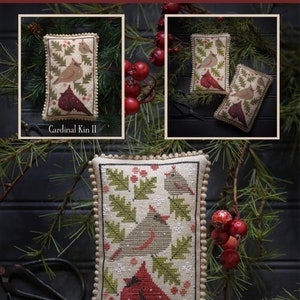 May include: A cross stitch pattern for a cardinal ornament. The pattern is called "Cardinal Kin" and is by Paulette Stewart. The pattern features two cardinals, holly leaves, and berries. The pattern is on a white background.