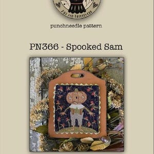 May include: A punchneedle pattern titled "PN366 - Spooked Sam" featuring a pumpkin-headed scarecrow design. The artwork is framed within a brown leather-like shape, measuring 4.75 x 5.5 inches. The image includes the artist's logo and website.