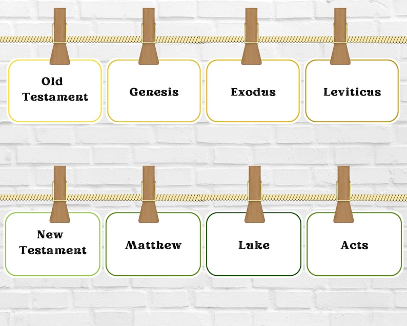 May include: A display of eight white cards with text from the Bible, including "Old Testament," "Genesis," "Exodus," "Leviticus," "New Testament," "Matthew," "Luke," and "Acts." Each card is held by a wooden clothespin and suspended by a gold rope against a white brick wall.