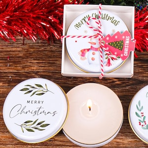 May include: Six round Christmas themed candle tins with various designs. The tins feature festive greetings like "Merry Christmas", "Warm Wishes", and "Happy New Year".