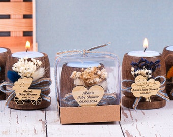 May include: A set of five small wooden candle holders with a blue and white theme. Each holder has a small candle, dried flowers, and a personalized tag with the text "Alvin's Baby Shower" and a date.