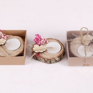 May include: Three small wooden candle holders with a tea light candle in each. The holders are decorated with dried flowers, twine, and a personalized wooden tag with the text "Duker & Adriana Oct 15, 2023".