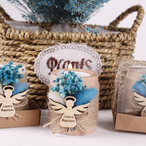 Pu&ograve; includere: Tre piccoli portacandele rustici con un angelo intagliato in legno e il testo "Liam's Baptism". Ogni portacandele &egrave; decorato con fiori secchi blu e bianchi e spago.