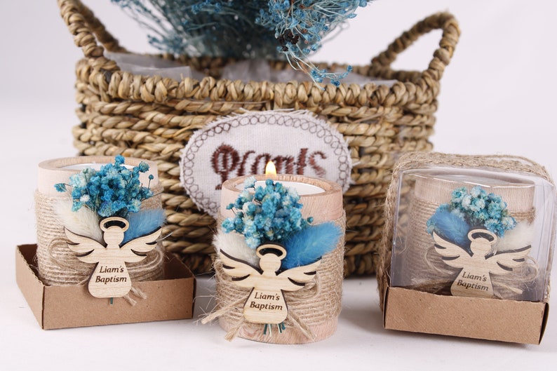 Pu&ograve; includere: Tre piccoli portacandele rustici con un angelo intagliato in legno e il testo "Liam's Baptism". Ogni portacandele &egrave; decorato con fiori secchi blu e bianchi e spago.