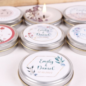 Peut inclure: Assortiment de petites bo&icirc;tes rondes en argent avec des &eacute;tiquettes blanches orn&eacute;es de motifs floraux et du texte "Emily & Daniel" avec une date de mariage. Les bo&icirc;tes contiennent de petites bougies.