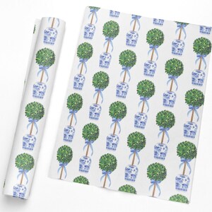 May include: White wrapping paper with a repeating pattern of green topiary trees in blue and white porcelain pots, tied with blue ribbons. A roll of the same paper is shown next to the flat sheet.