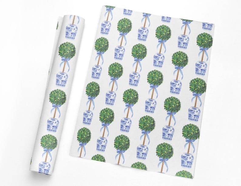 May include: White wrapping paper with a repeating pattern of green topiary trees in blue and white porcelain pots, tied with blue ribbons. A roll of the same paper is shown next to the flat sheet.