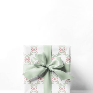 May include: A white gift box with a green ribbon and a pattern of pink bows and green leaves.