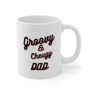 Puede incluir: Taza de cerámica blanca con texto negro que dice "Groovy & Cheugy Dad" en una fuente retro. El texto tiene un contorno rosa.