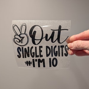 May include: A black glitter vinyl decal with a peace sign and the text "Out Single Digits #I'm 10".