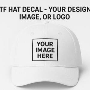 Pode incluir: Boné de beisebol branco com aba curva. O boné apresenta um design quadrado na frente com o texto "YOUR IMAGE HERE" dentro de uma borda preta. Acima do boné está o texto "DTF HAT DECAL - YOUR DESIGN, IMAGE, OR LOGO".
