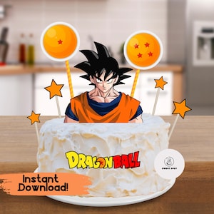 May include: A white frosted cake decorated with a Dragon Ball Z theme. The cake features a Goku character topper, two orange and yellow sphere toppers, and star-shaped accents. The words "Dragon Ball" are displayed in yellow and red. Text reads "Instant Download!"