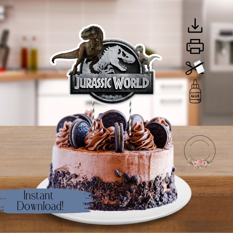May include: A chocolate cake with Oreo cookie crumbs and frosting, topped with a Jurassic World cake topper featuring a dinosaur silhouette and the text "Jurassic World".