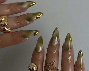 Uñas postizas de lujo: ojo de gato verde, punta francesa dorada y brillo aterciopelado.
