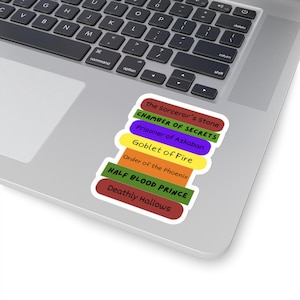 May include: A stack of colorful stickers with the titles of the Harry Potter books. The stickers are rectangular with rounded edges and are arranged in a vertical stack. The titles include "The Sorcerer's Stone" and "Deathly Hallows".