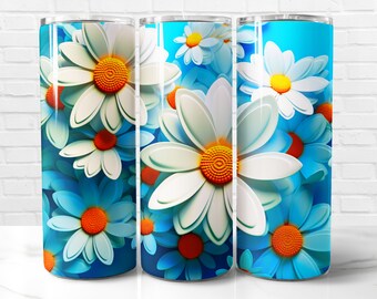 May include: A floral tumbler featuring a repeating pattern of white daisies with orange centers and blue petals. The design is set against a gradient blue background. The tumbler is cylindrical and appears to be made of stainless steel.