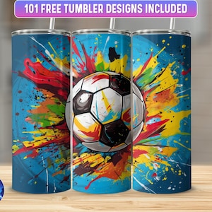 Może przedstawiać: Trzy kubki ze stali nierdzewnej z kolorowym abstrakcyjnym wzorem rozprysku farby i piłką nożną w środku. Kubki stoją na drewnianej powierzchni.