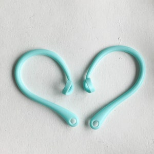 May include: Two light blue silicone ear hooks for headphones. The hooks are designed to fit over the ear and help keep headphones in place.
