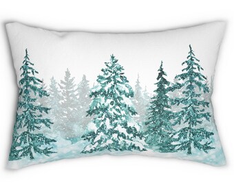 May include: Rectangular white pillow with a winter forest design. The design features teal-colored evergreen trees with a snowy effect. The trees are arranged in a forest scene against a white background, creating a winter theme.