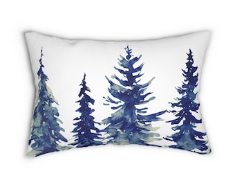 May include: A rectangular white pillow featuring a watercolor design of four stylized evergreen trees in shades of blue and gray. The trees are arranged in a row against a white background, creating a serene, nature-inspired aesthetic.