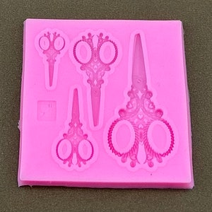 May include: Pink silicone mold with four detailed designs of ornate scissors. The mold is perfect for making fondant or gum paste decorations for cakes or cupcakes.