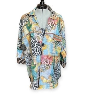 May include: A multi-colored button-up shirt with a patchwork design featuring a leopard print pattern. The shirt has a collar and long sleeves.