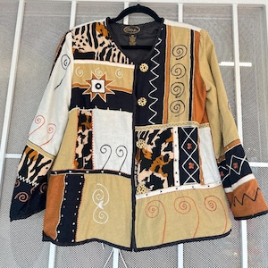 May include: A patchwork jacket with a variety of patterns and textures. The jacket features animal print, geometric shapes, and embroidered details in shades of beige, black, and brown. It has gold-colored buttons and a black collar.